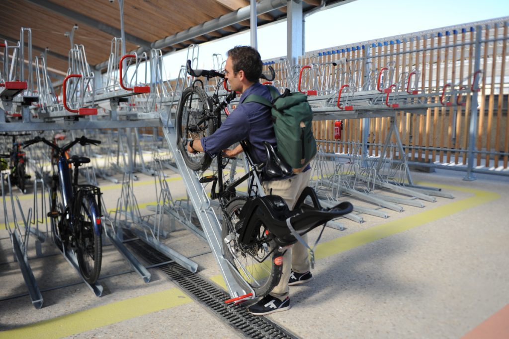 Un cycliste stationne son vélo sur un des racks de stationnement en double étage Optima V10 dans le parking Vélos de la Gare du Nord